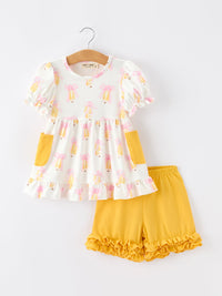 Girls back-to-school set: white top with pink bows and yellow pockets, paired with mustard-yellow ruffle shorts.