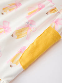 White fabric with pink bow print and yellow cuff trim from Girls Back To School Bow Pocket Ruffle Top Shorts Set.