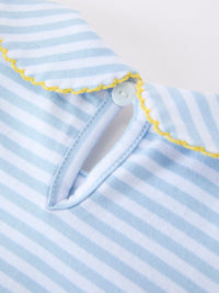 Close-up of light blue and white striped fabric with yellow zigzag stitching and a pale blue button.