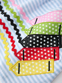 Colorful crayon-shaped appliques with white polka dots and rainbow zigzag trim on light blue striped fabric