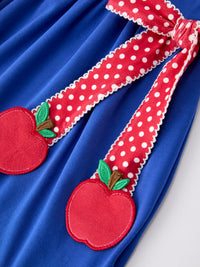 Blue dress with red apple appliques on polka-dot straps and white trim.