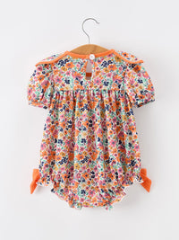 Orange floral girls romper with petals collar, contrast trim, eyelet detailing and puff sleeves.