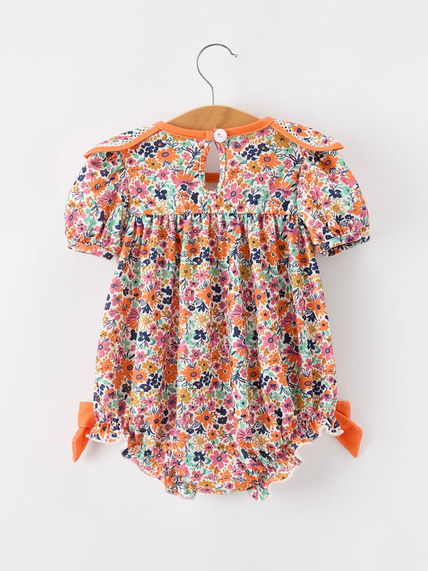 Orange floral girls romper with petals collar, contrast trim, eyelet detailing and puff sleeves.
