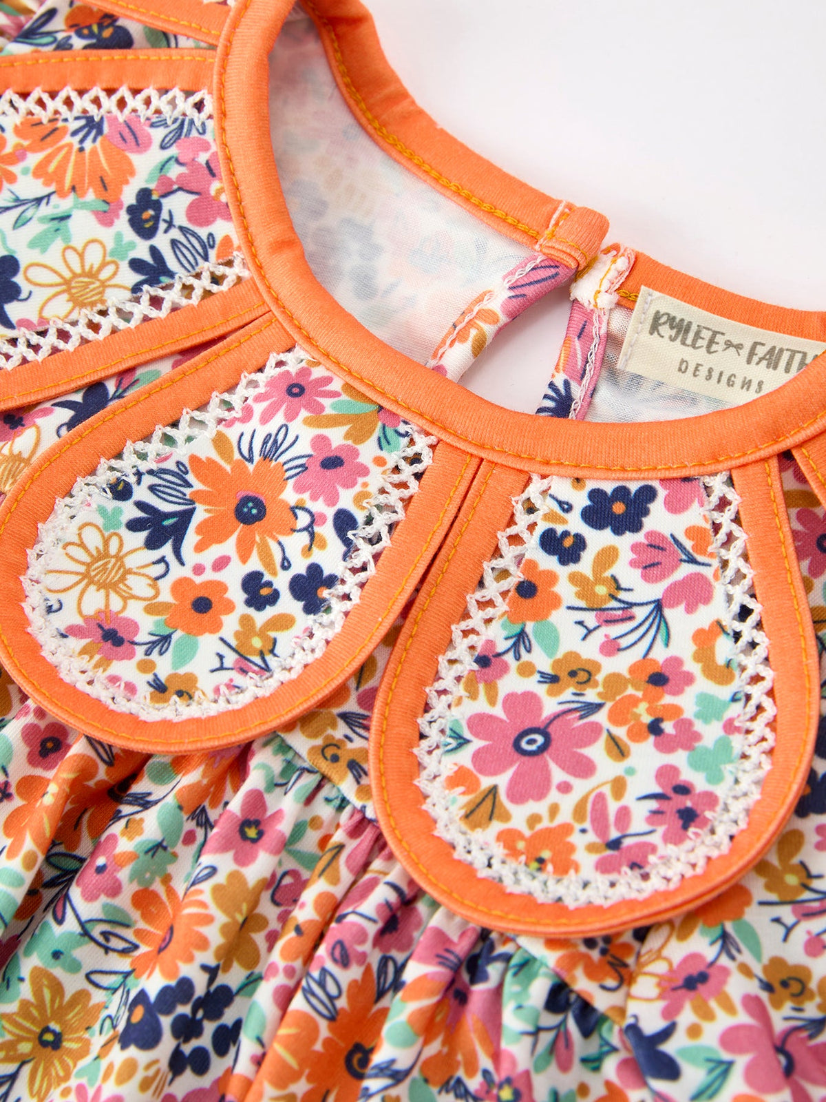 Orange-trim floral romper with petals collar, white eyelet edging, colorful bloom print RPG63