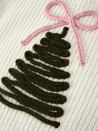 A close-up of a knitted textile featuring a stylized Christmas tree in dark olive green yarn with a pink yarn bow on a cream-colored knit background.