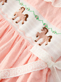 Pink smocked bodice girls dress featuring Western horse embroidery, lace trim, and dotted poly skirt fabric.