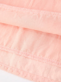Close-up of pink smocked girls dress fabric featuring delicate embroidery stitching and textured cotton material.