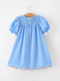 Blue baby girl dress on hanger with puff sleeves, lace trim, white buttons, dotted fabric and scalloped orange hem