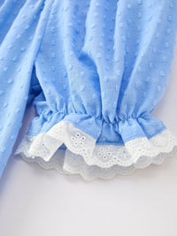 Blue baby dress close-up with dotted fabric and white lace trim, smocked waist detail.