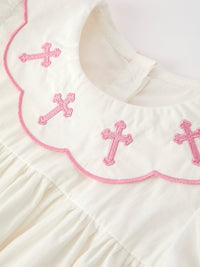 Pink cross embroidery on scalloped collar of ivory girls christening dress with pink trim details
