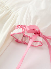 Pink ribbon tie detail on ivory puff sleeve with scalloped pink trim for a girls baptism dress