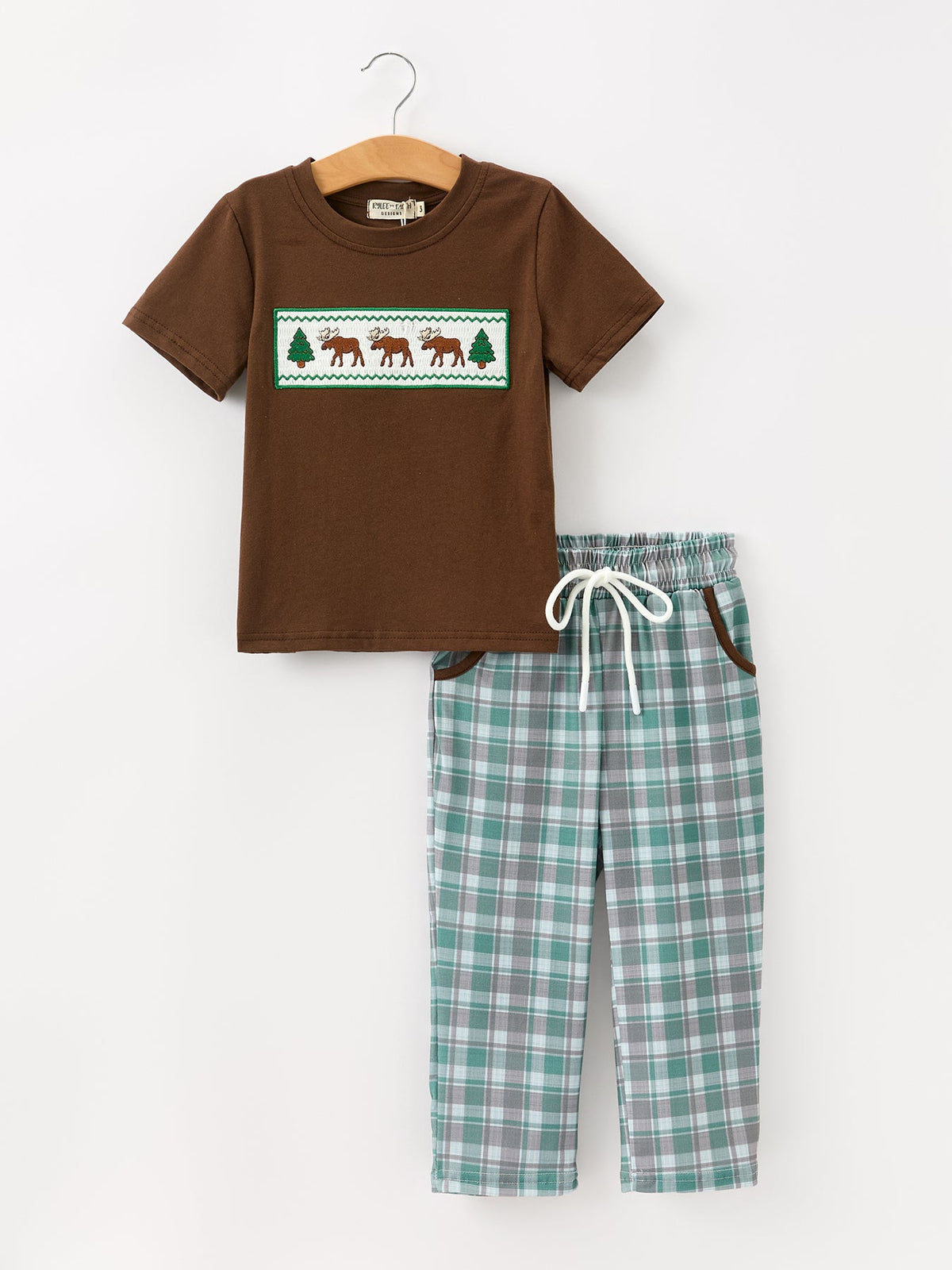 Boy's brown short-sleeve top with white smocked chest featuring moose and pine tree embroidery, paired with green plaid