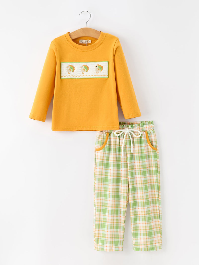 Mustard yellow long sleeve top with white smocked turkey embroidery paired with green orange plaid pants and elastic waist