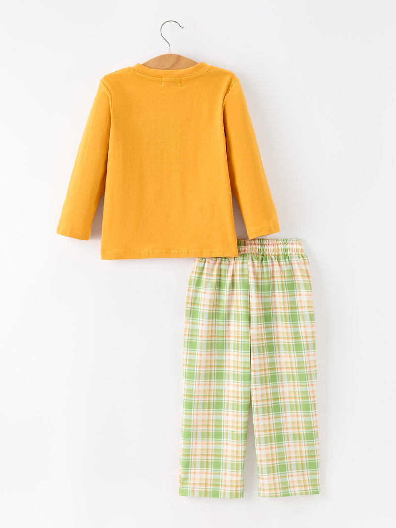 Back view of mustard yellow shirt on wooden hanger above green orange plaid pants with gathered elastic waistband