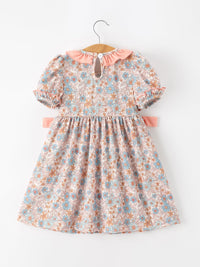Fall floral dress for girls with pink smocked detailing, puff sleeves, ruffle neck, and bow accents.