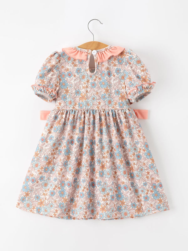 Fall floral dress for girls with pink smocked detailing, puff sleeves, ruffle neck, and bow accents.