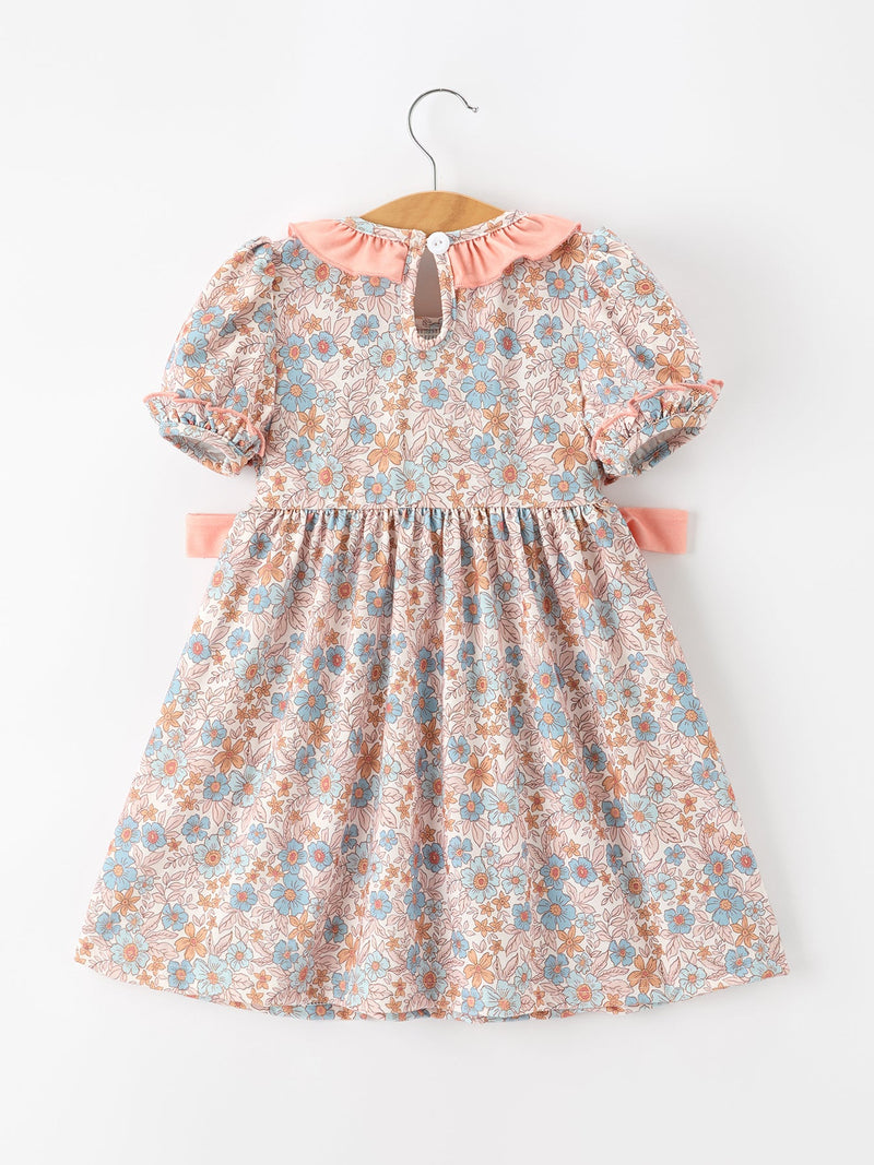 Fall floral dress for girls with pink smocked detailing, puff sleeves, ruffle neck, and bow accents.
