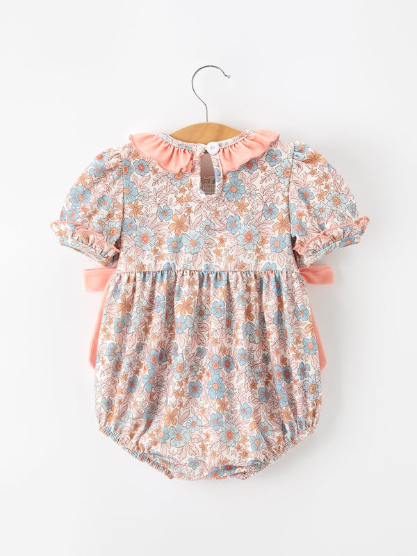 Fall floral baby romper with smocked neck and ruffle pink bow, blue blossoms on peach fabric.