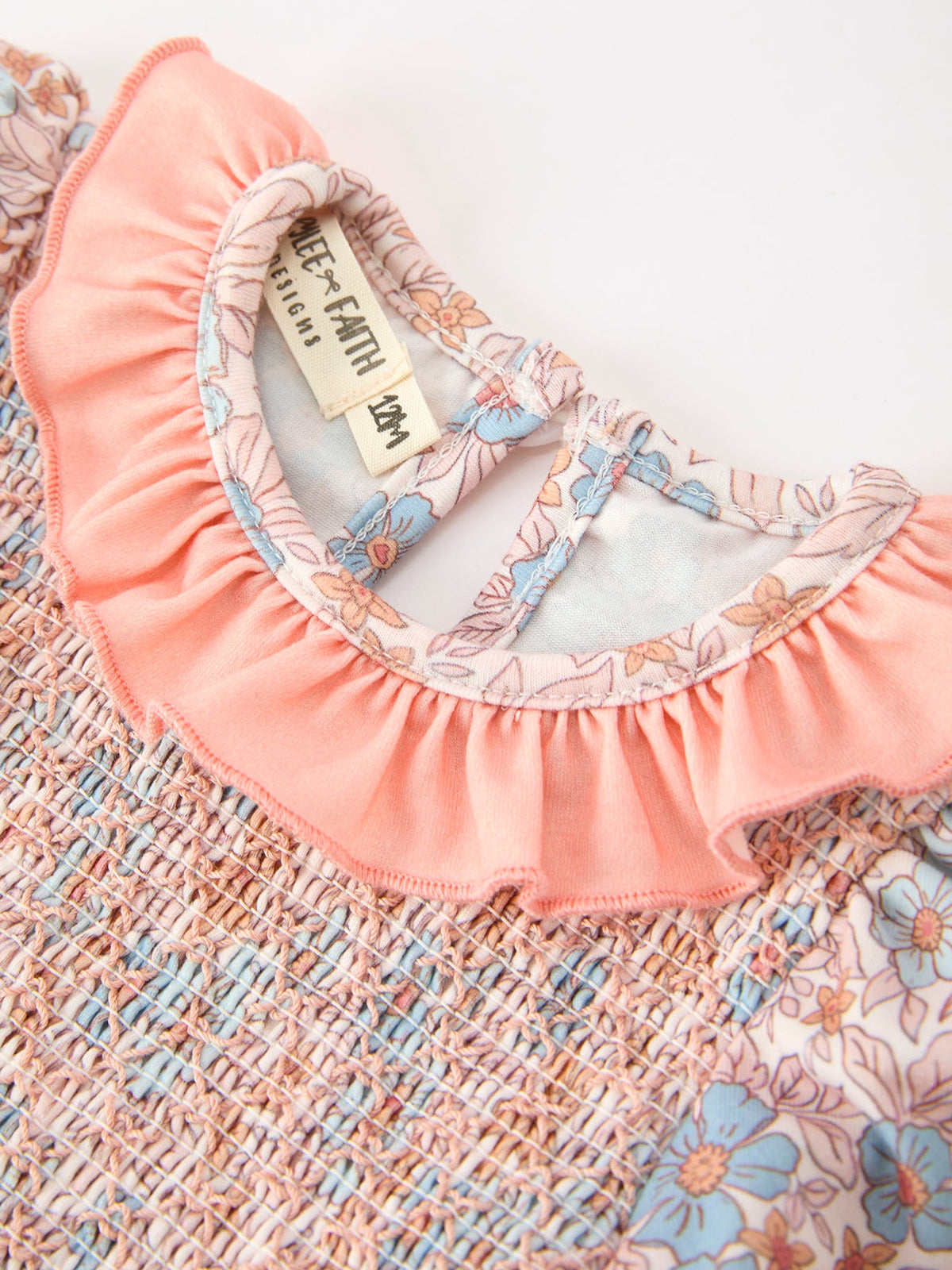 Fall floral baby romper with smocked bodice, ruffle neck, and bow accents in pink pastel print.