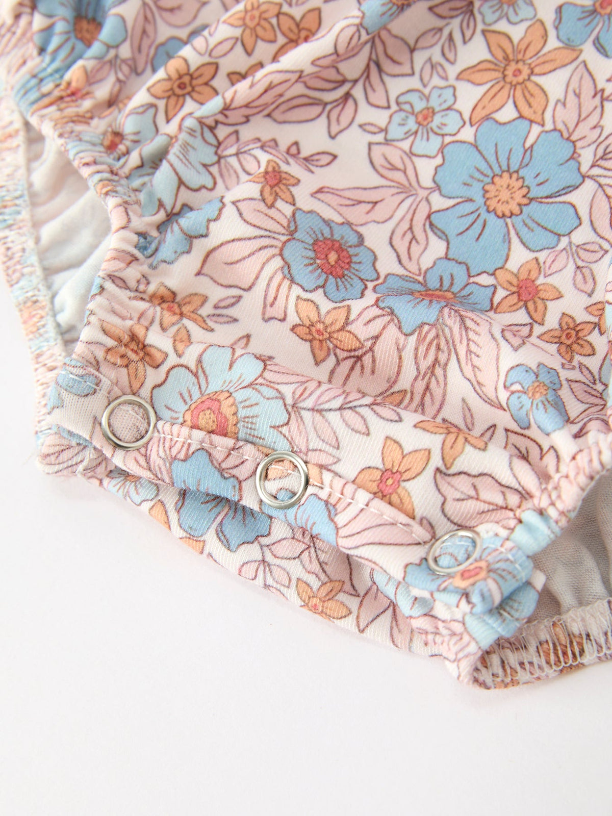 Fall Floral Baby Romper with smocked detailing and bow accents in pink-blue floral print.