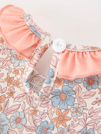Close-up of Fall floral baby romper fabric with smocked ruffle neck and button closure.