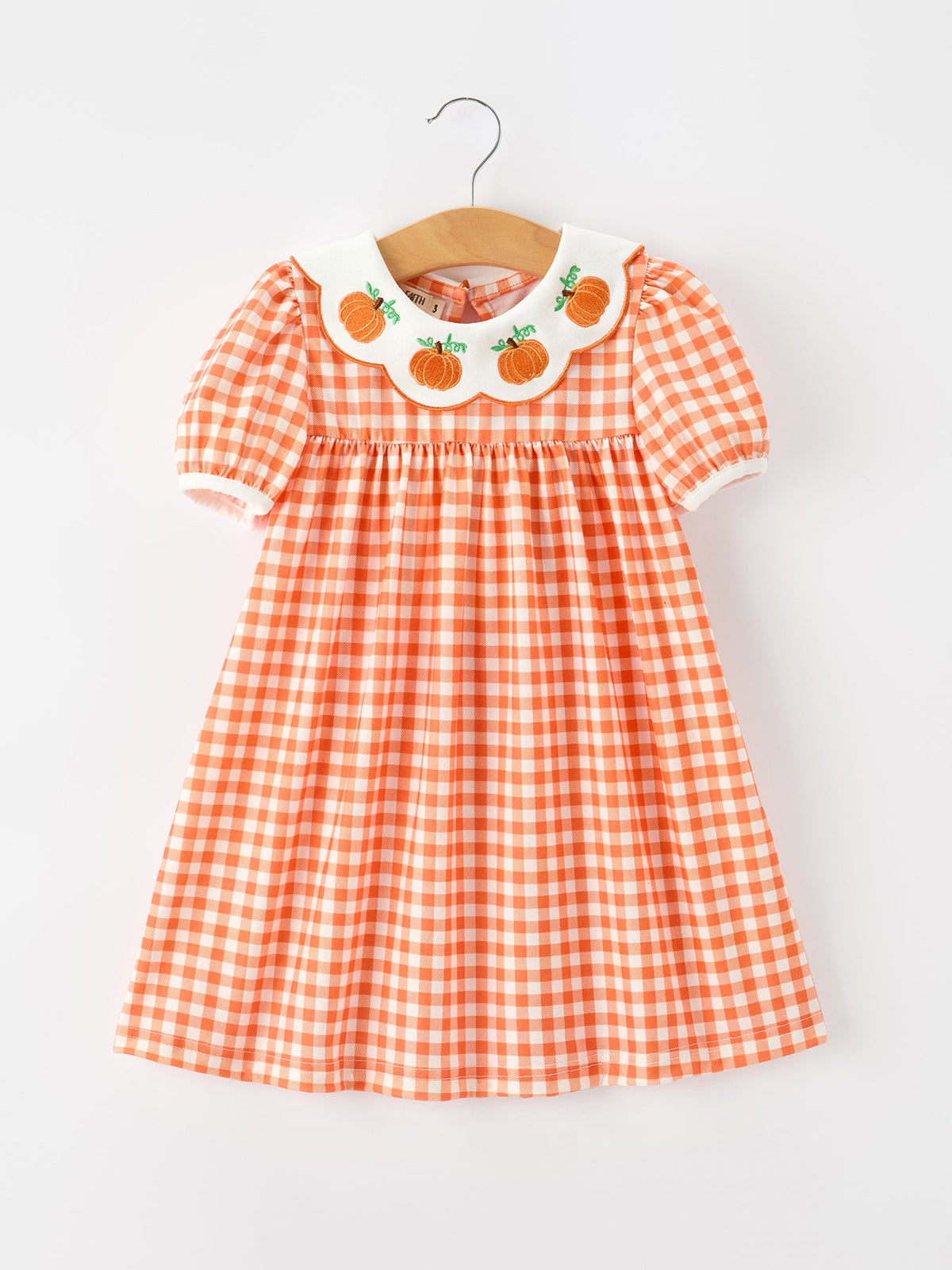 Orange gingham girls dress with puff sleeves and white scalloped collar featuring embroidered pumpkins for fall.