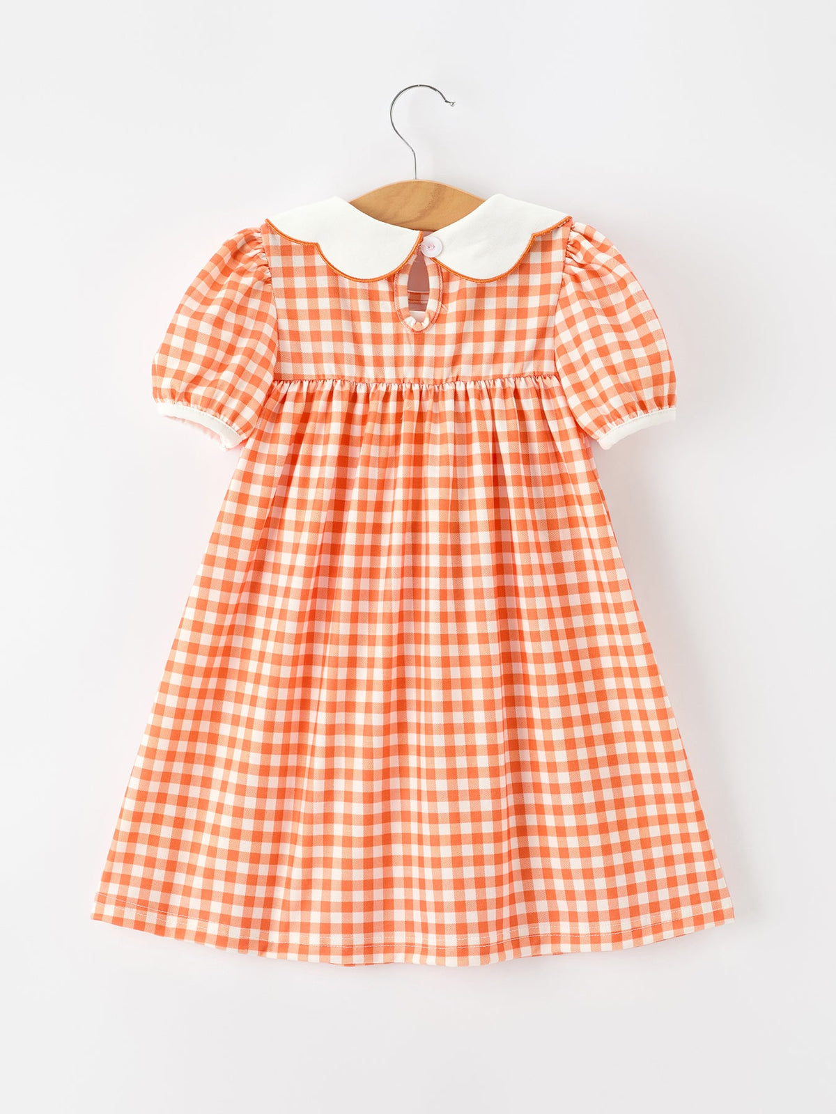 Orange gingham girls dress with puff sleeves, white Peter Pan collar, and pumpkin-embroidered keyhole neckline for fall.