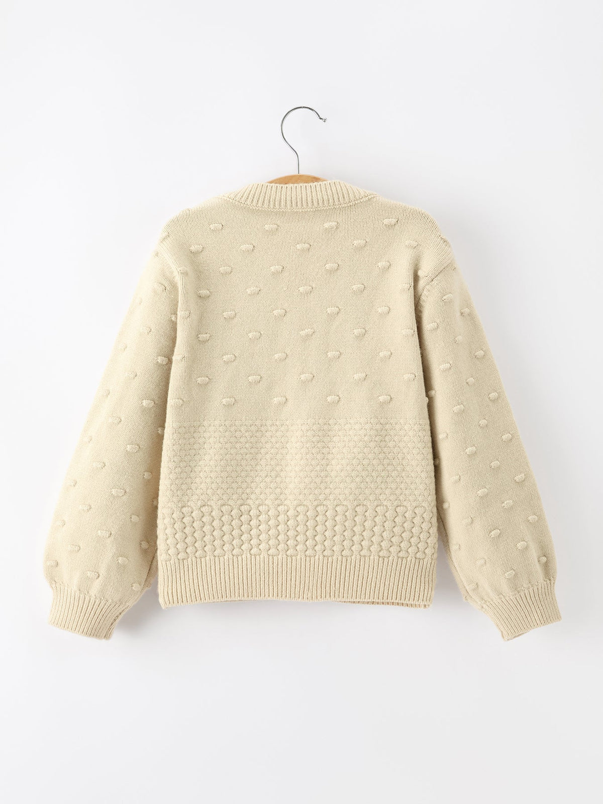 Back of cream kids knit cardigan featuring textured dot pattern and ribbed hem for festive holiday wear.