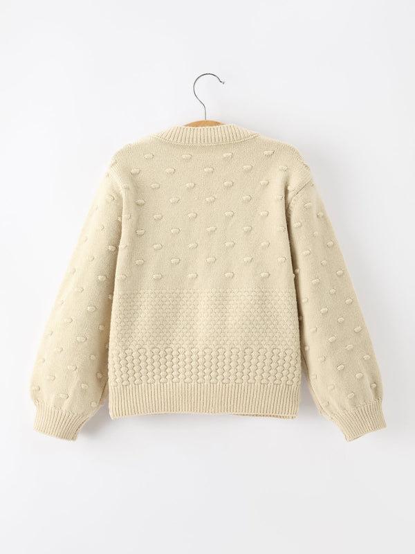 Back of cream kids knit cardigan featuring textured dot pattern and ribbed hem for festive holiday wear.