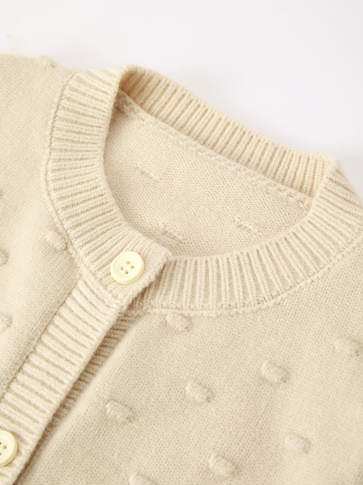 Beige knit cardigan with ribbed collar and buttons, featuring soft textured fabric for cozy kids' holiday wear.