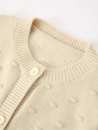 Beige knit cardigan with ribbed collar and buttons, featuring soft textured fabric for cozy kids' holiday wear.
