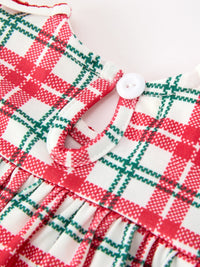 Close-up of red and green plaid baby romper with white button keyhole back and festive ruffled fabric.