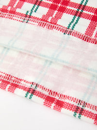 Red and green plaid baby dress fabric featuring delicate white overlock stitching and festive holiday pattern details.