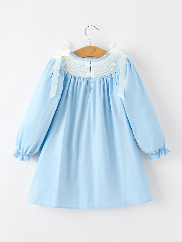Blue girls Christmas dress with white smocked neckline, long puff sleeves, and white bow shoulder straps.