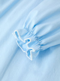 Light blue puff sleeve cuff with white ruffled trim on a Christmas nativity smocked girls dress.