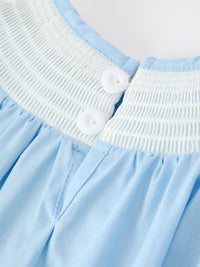 Close-up of white smocked neckline and white buttons on a Boca blue baby bubble romper with gathered fabric details.