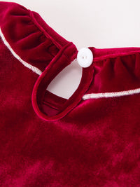 Burgundy velvet baby romper detail showing ruffled collar with white trim and white button closure.