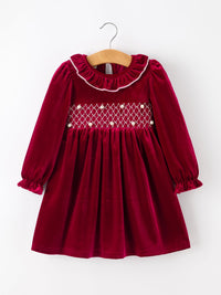 Burgundy velvet girls Christmas dress with smocked pearl bodice, ruffled neckline, and long puff sleeves.