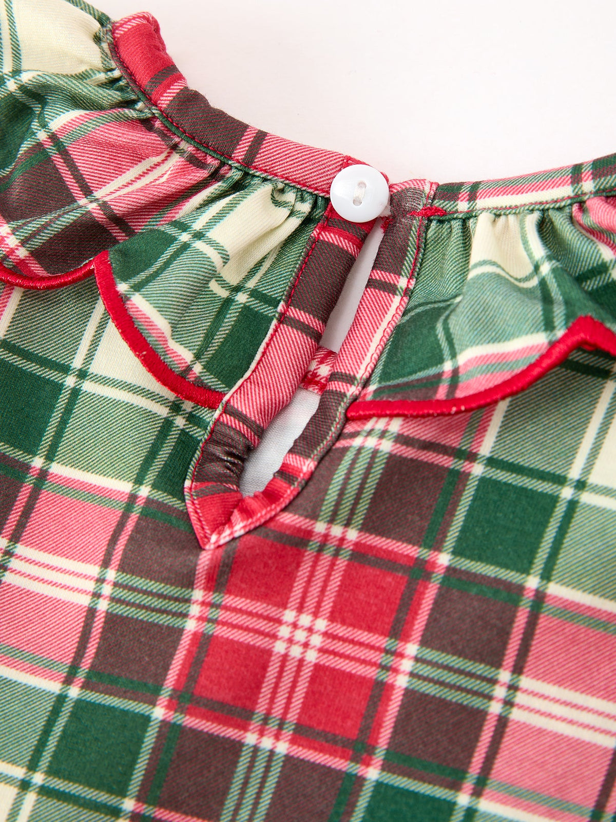 Red green and ivory plaid girls dress featuring a ruffle collar with red piping and white button back closure.