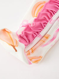 Pink ruffled trim along the zipper of a baby girls pumpkin print romper with enclosed feet and sweet fall-inspired details.