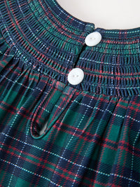 Green, navy, and red plaid girls dress with round smocked yoke, two white buttons, and detailed stitching.