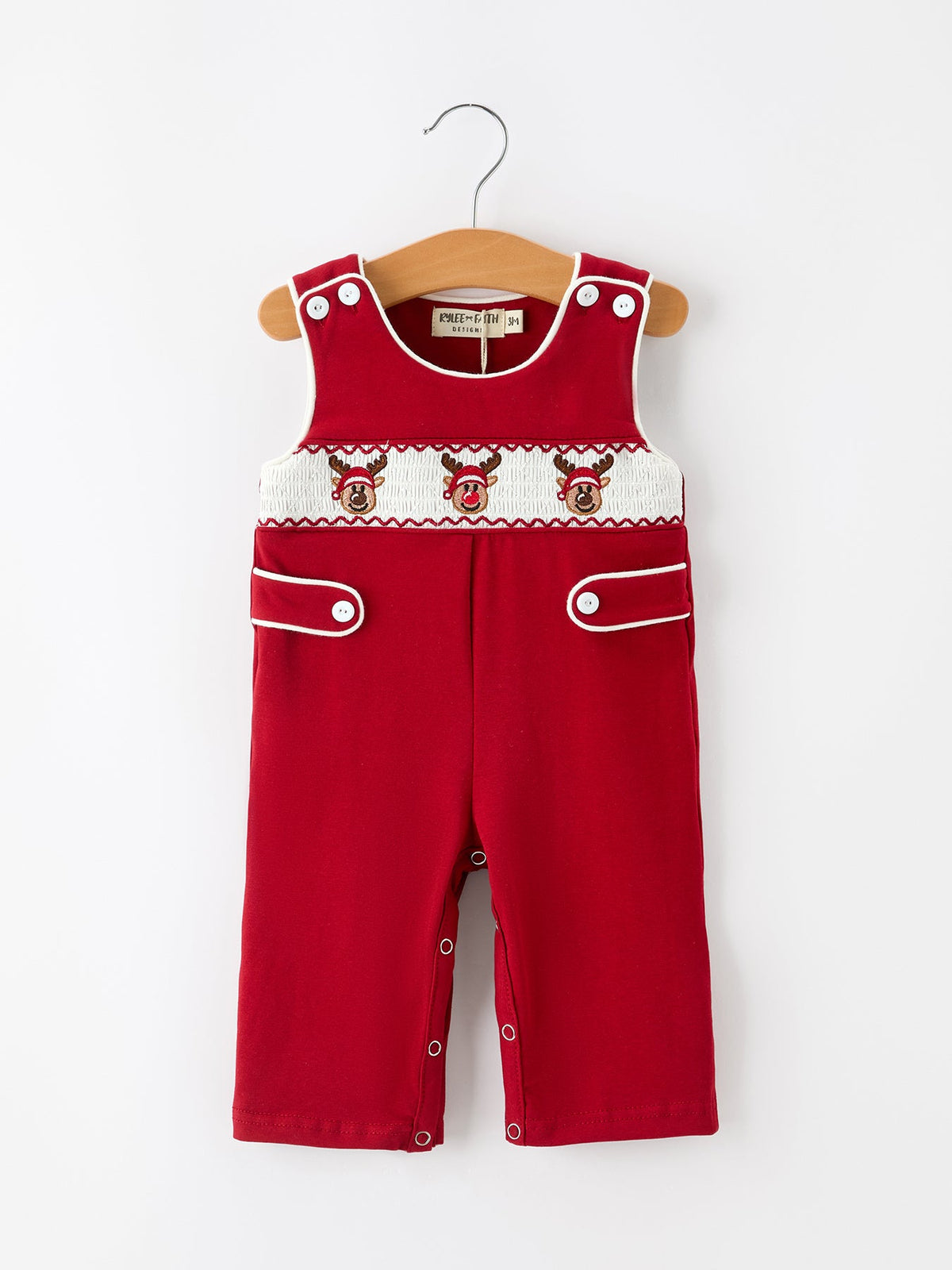 Red sleeveless baby romper with smocked reindeer chest panel, white contrast piping, button tabs, and leg snaps.