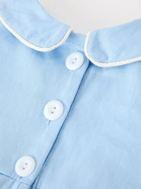 Light blue cotton romper featuring a white piped Peter Pan collar and white snap buttons down the front placket.