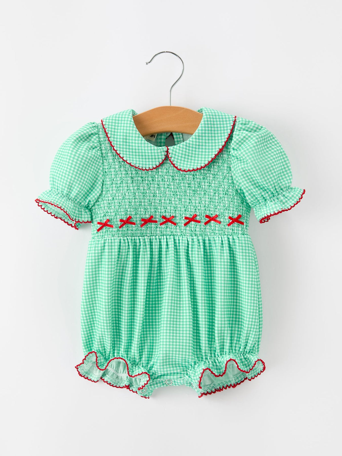 Green plaid bubble romper with smocked bodice, red cross-stitch details, Peter Pan collar, and ruffled legs for festive holiday wear.