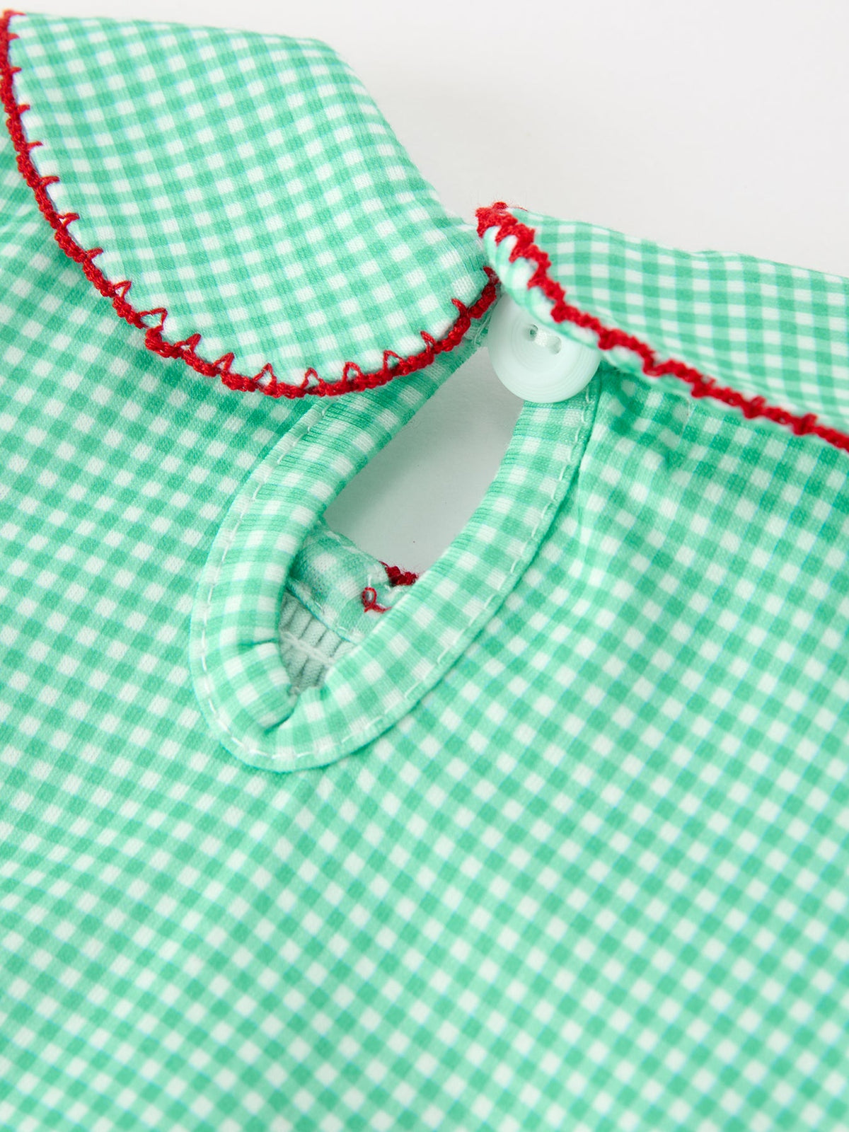 Green plaid girls romper with red embroidered Peter Pan collar, smocked bodice, and white snap button for festive holiday wear.