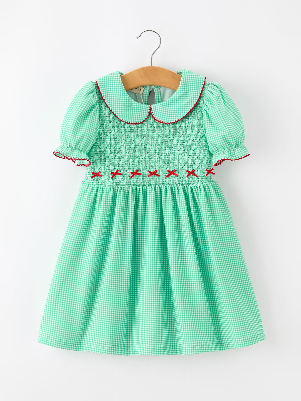 Green gingham girls Christmas dress with smocked bodice, red bow details, Peter Pan collar, and puff sleeves.