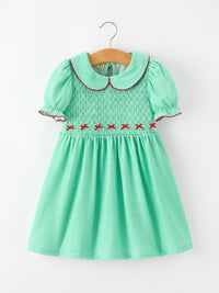 Green gingham girls Christmas dress with smocked bodice, red bow details, Peter Pan collar, and puff sleeves.