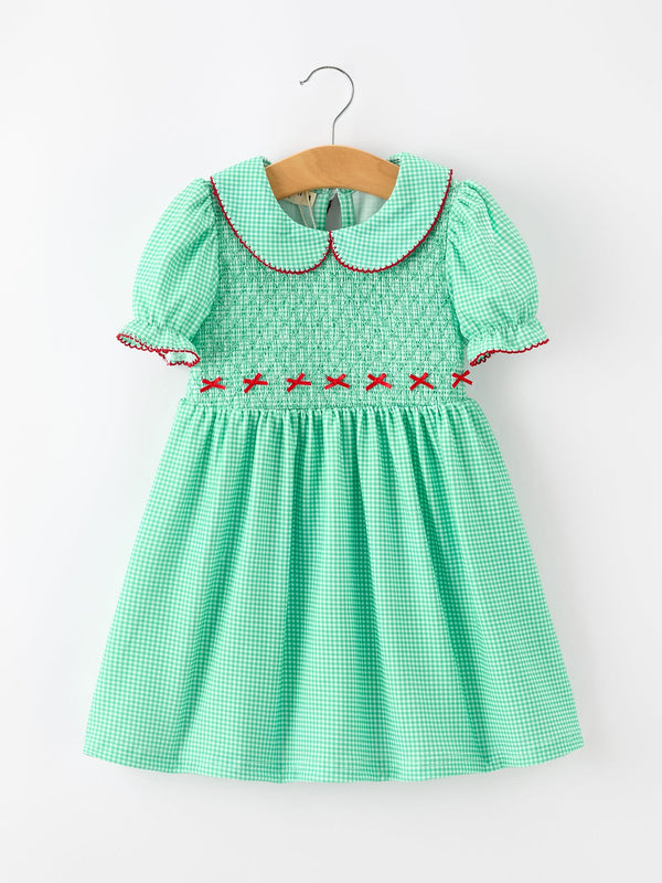 Green gingham girls Christmas dress with smocked bodice, red bow details, Peter Pan collar, and puff sleeves.