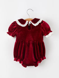 Burgundy velvet baby girl romper with lace-trim Peter Pan collar, puff sleeves, and ruffled hem for festive holiday wear.