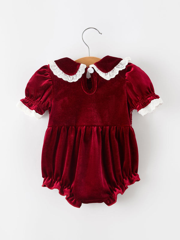 Burgundy velvet baby girl romper with lace-trim Peter Pan collar, puff sleeves, and ruffled hem for festive holiday wear.